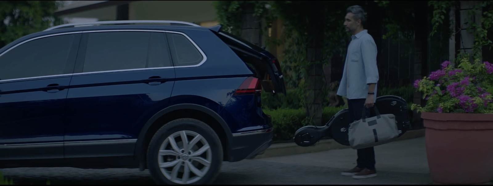 a man standing next to a blue volkswagen suv