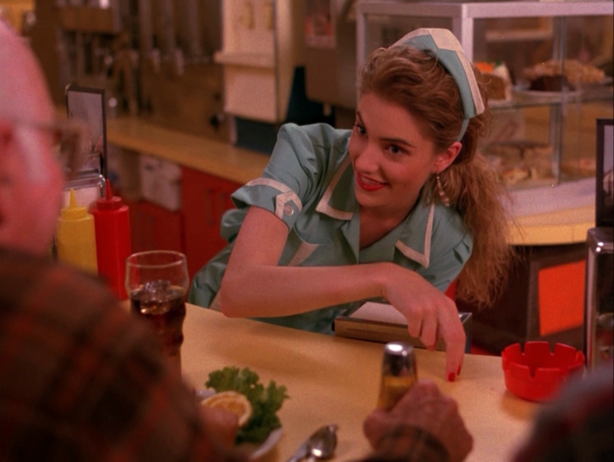 a woman sitting at a table with a knife in her hand