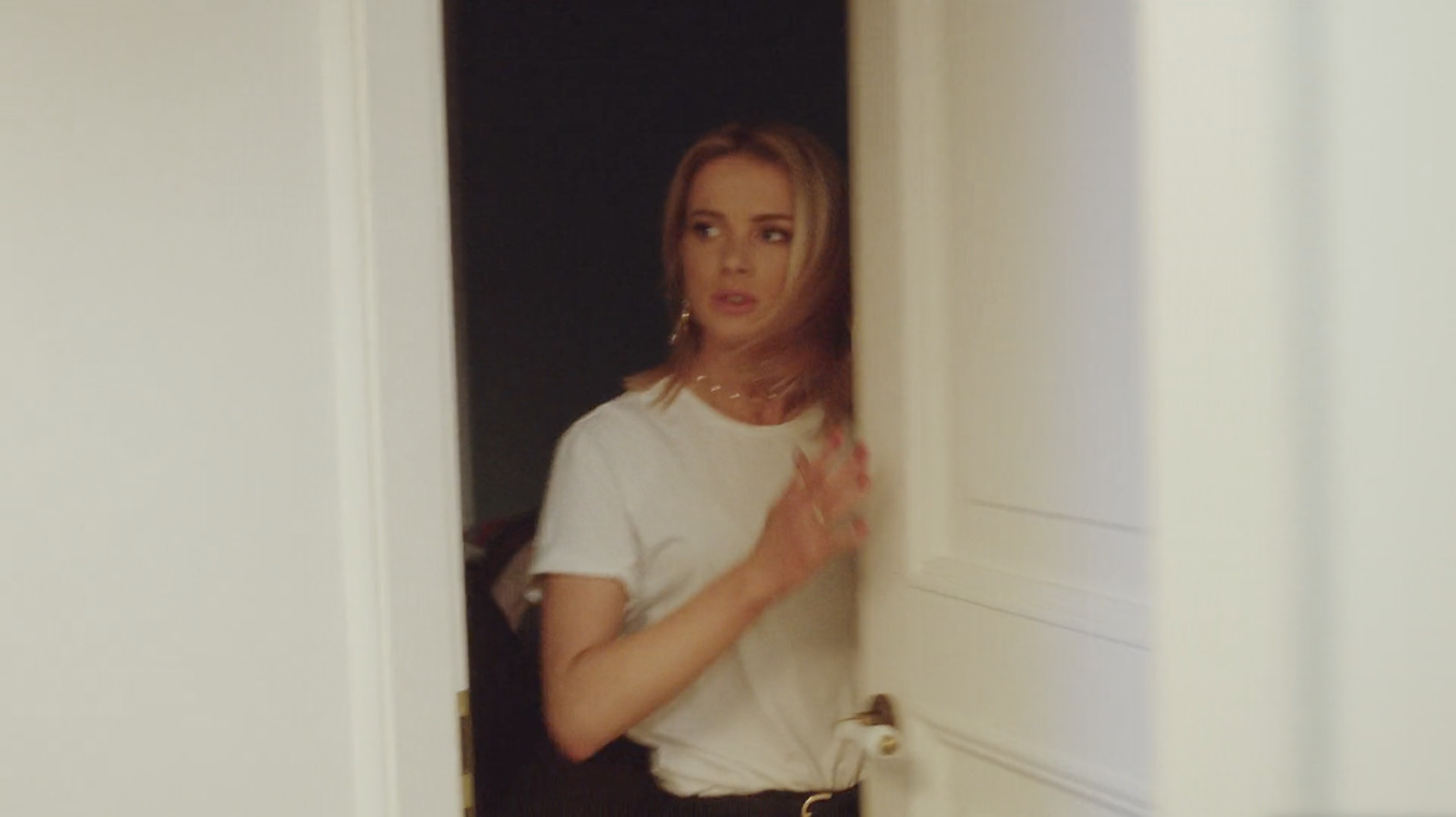 a woman in a white shirt is standing in a doorway