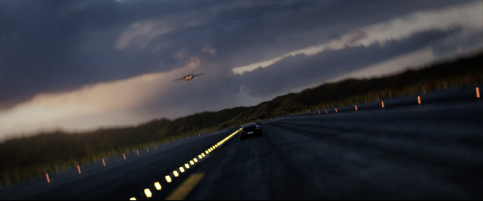 a car driving down a road under a cloudy sky