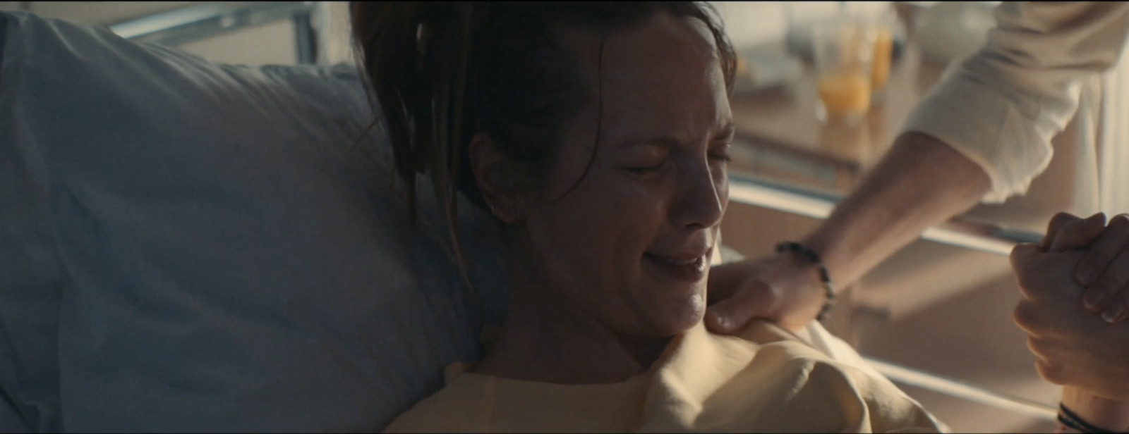 a woman laying in a hospital bed with her hand on her shoulder