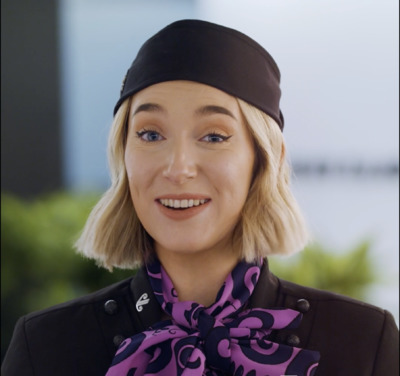 a woman with blonde hair wearing a black hat and purple scarf