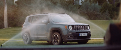 a jeep driving down a street next to a lush green field