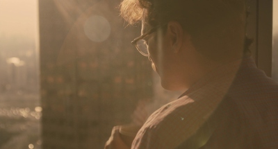 a man with glasses looking out of a window