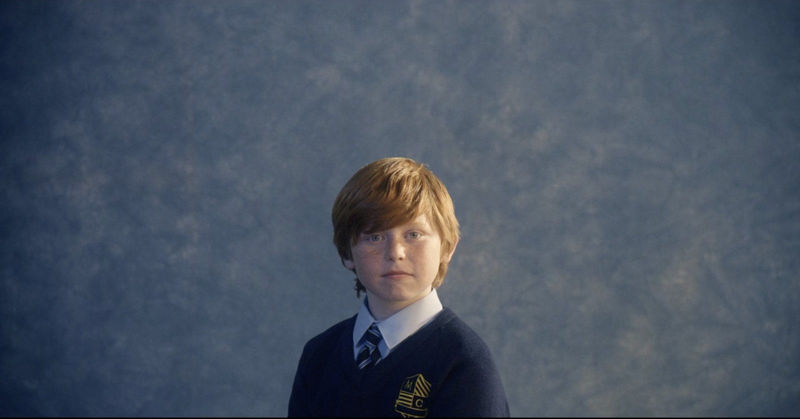 a young boy wearing a sweater and tie