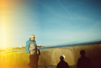 a man standing next to a wall near the ocean