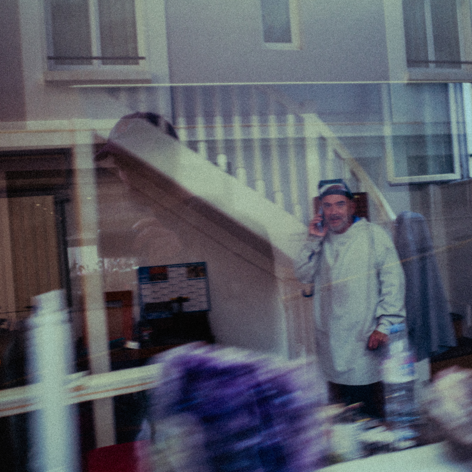 a man talking on a cell phone next to a staircase