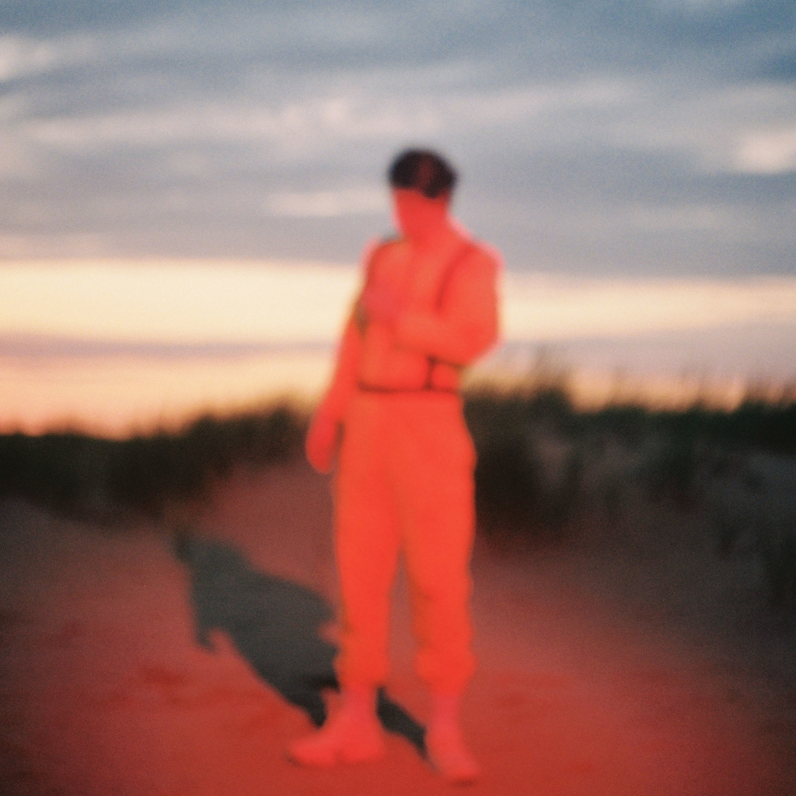 a man in an orange jumpsuit standing on a dirt road