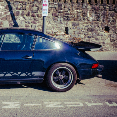 a blue car parked in front of a stone wall