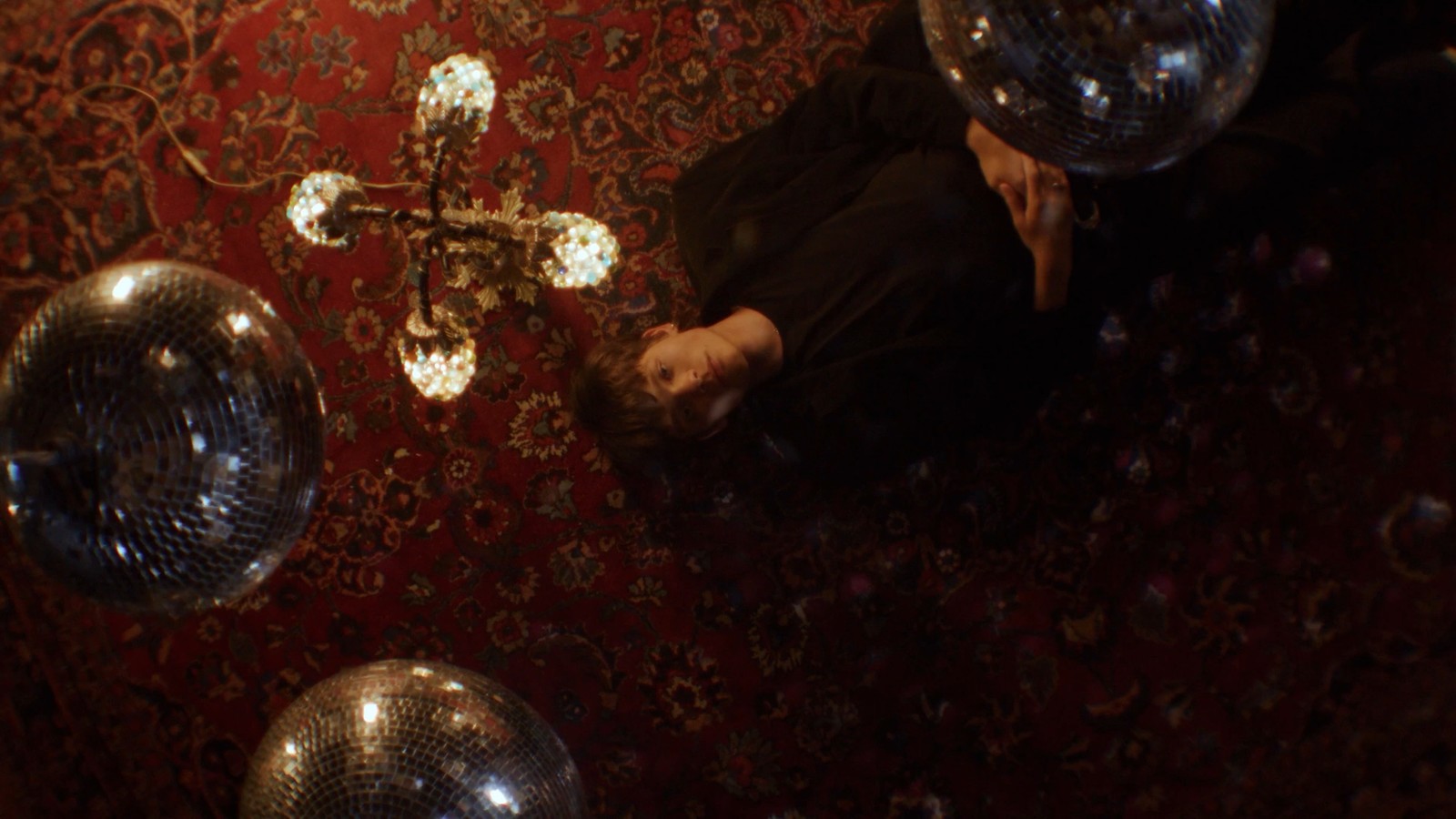 a man laying on the floor surrounded by disco balls