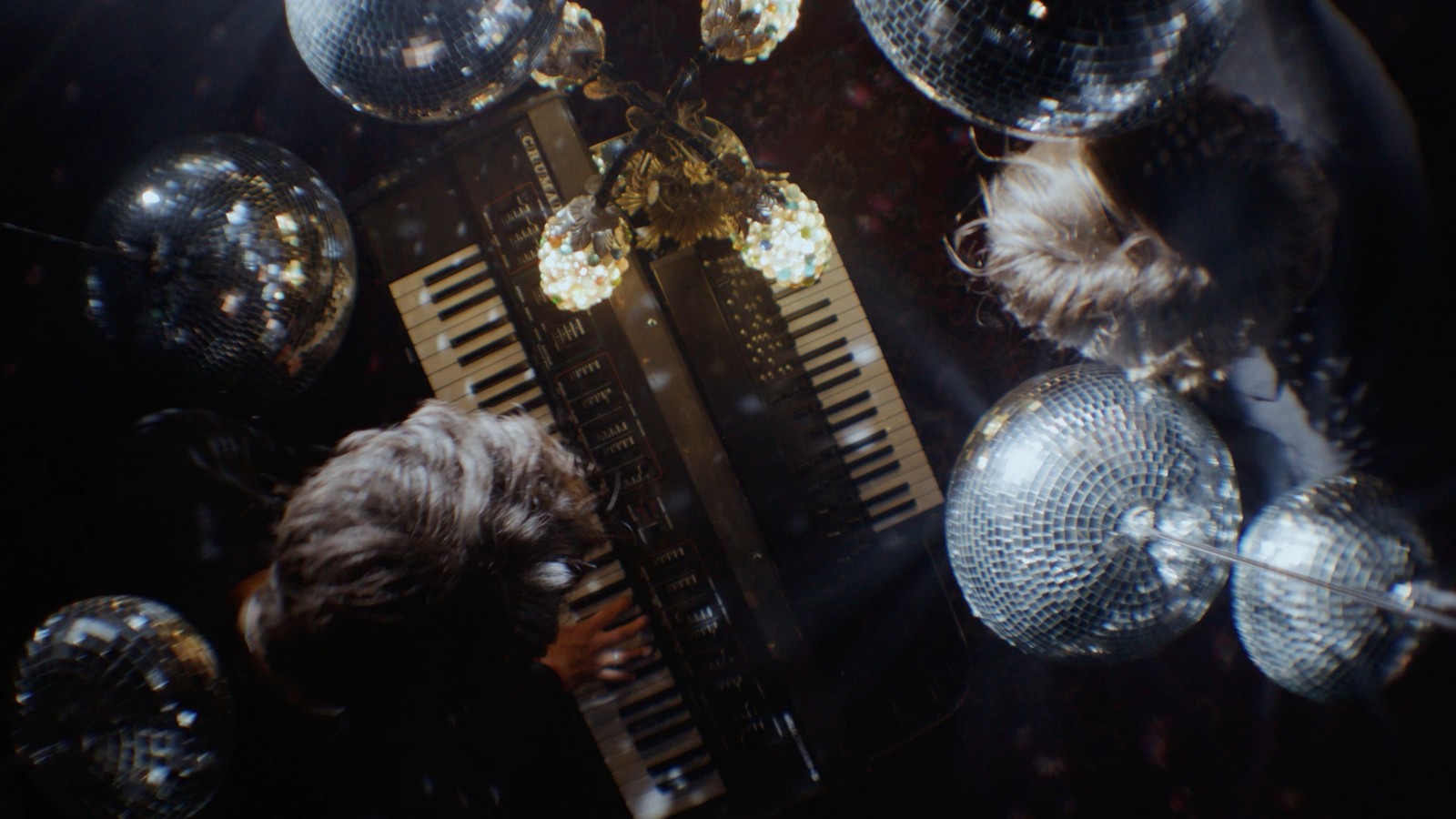 a person playing a keyboard in front of disco balls