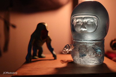 a glass bottle with a face on it next to a figurine