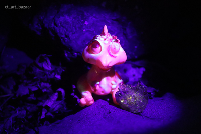 a pink toy sitting on top of a purple rock