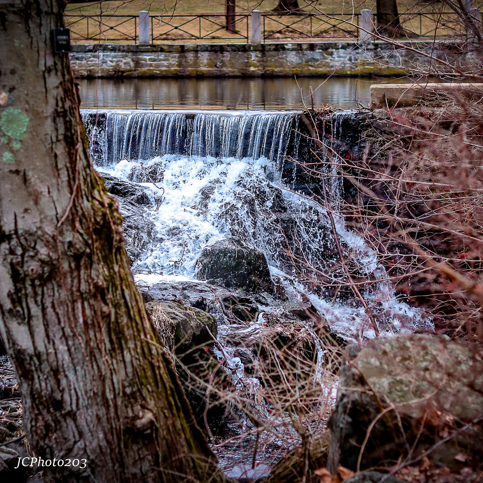 a small waterfall in a wooded area next to a bridge