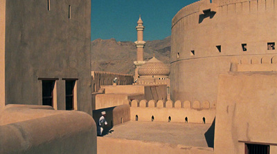 a person sitting on a ledge in front of a building