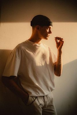 a man standing in front of a wall smoking a cigarette