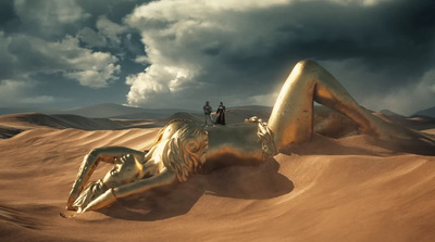 two people standing on top of a golden horse in the desert