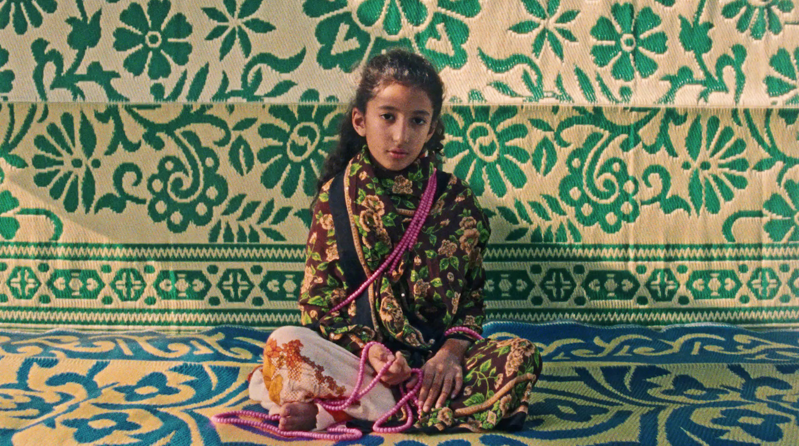 a little girl sitting on a colorful rug