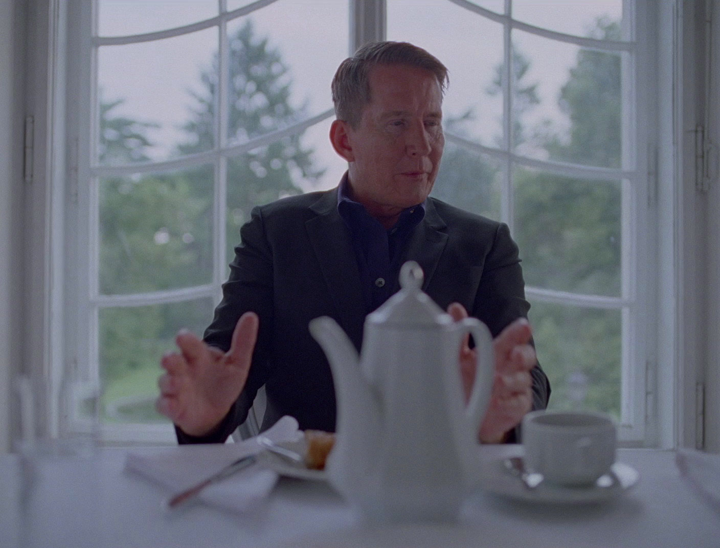 a man sitting at a table in front of a window