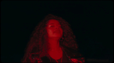 a woman with long curly hair singing into a microphone