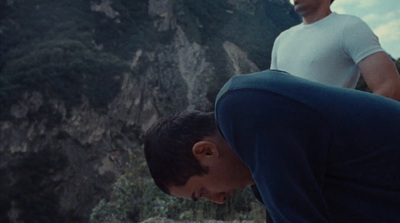 two men standing next to each other in front of a mountain