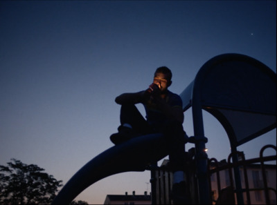 a man sitting on top of a slide talking on a cell phone