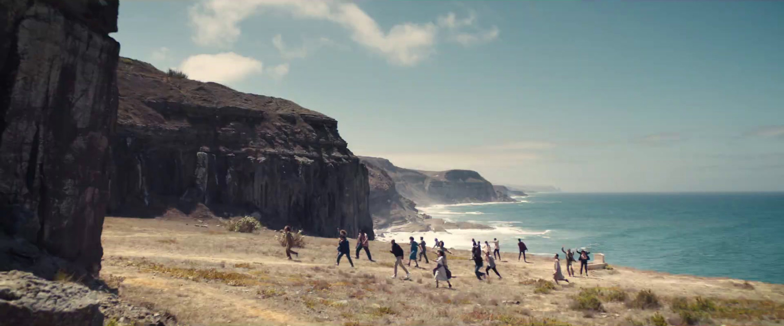 a group of people walking along a beach next to the ocean