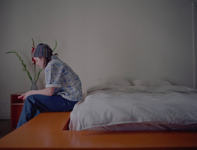 a woman sitting on a bed next to a plant