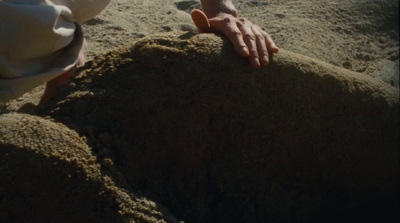 a person reaching for something in the sand