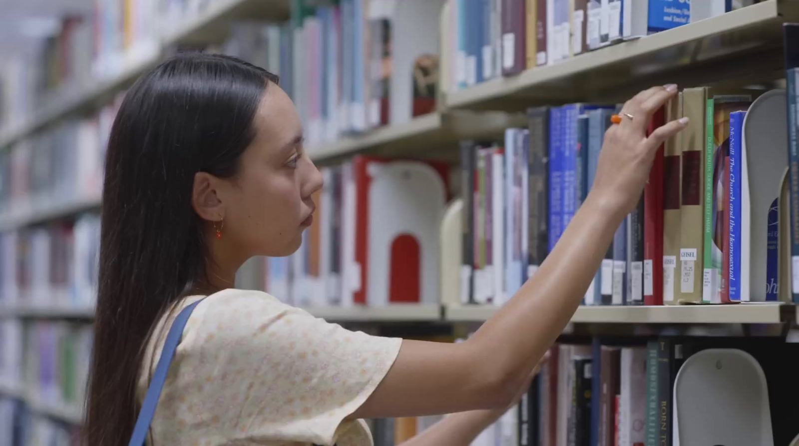 a woman reaching for a book in a library