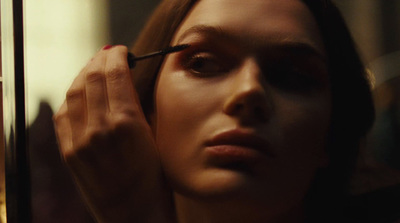 a woman is doing makeup in front of a mirror