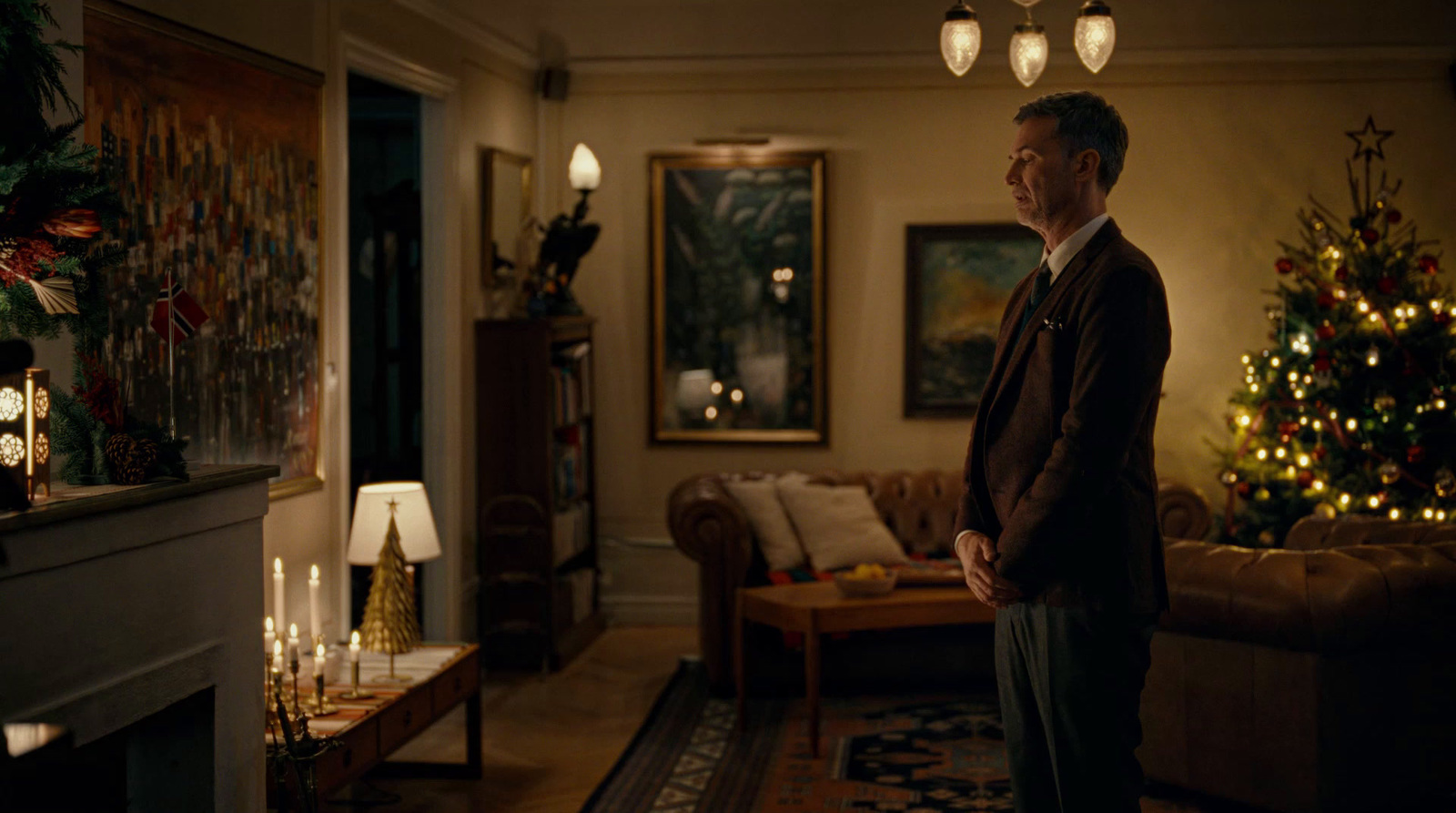 a man standing in a living room next to a christmas tree