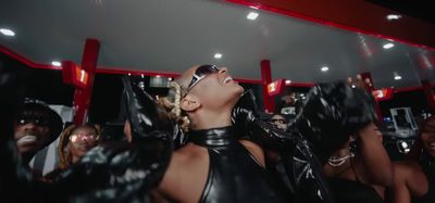 a woman in a black leather outfit with her hands in the air