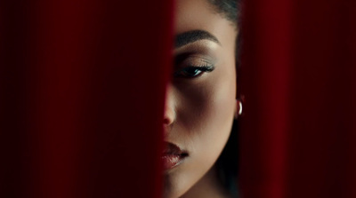 a woman looking through a red curtain