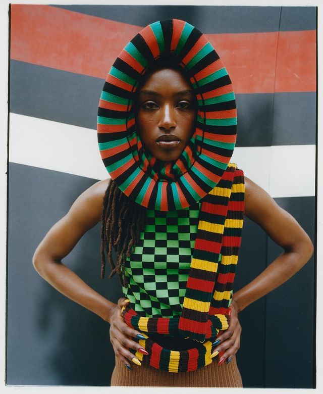 a woman with dreadlocks standing in front of a wall