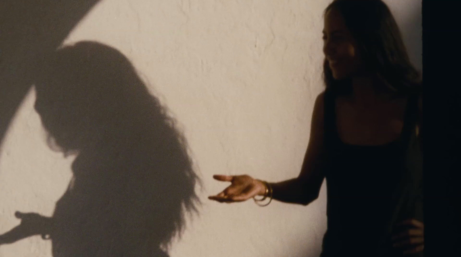 a woman standing next to a wall with a shadow on it