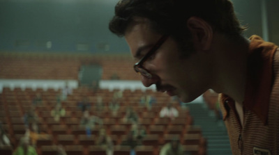 a man with glasses standing in front of a crowd of people