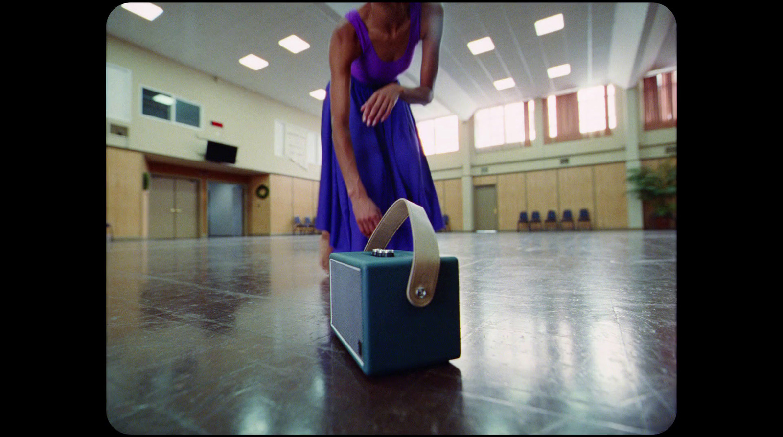 a woman in a purple dress is standing on a suitcase