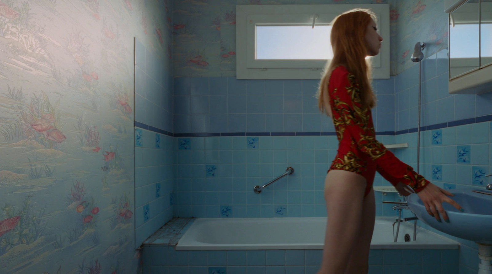 a woman standing in a bathroom next to a sink