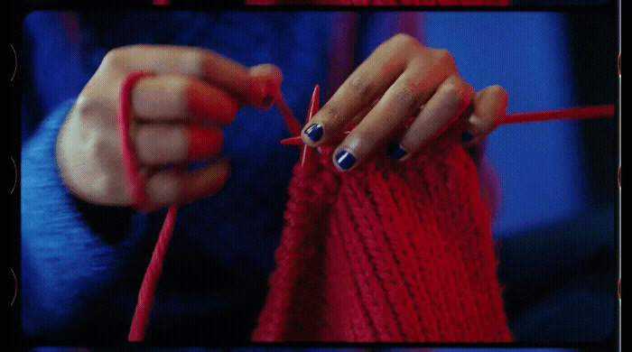 a woman knitting a red piece of yarn