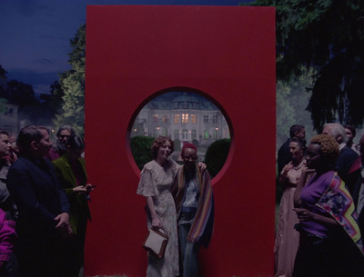 a group of people standing around a red sculpture