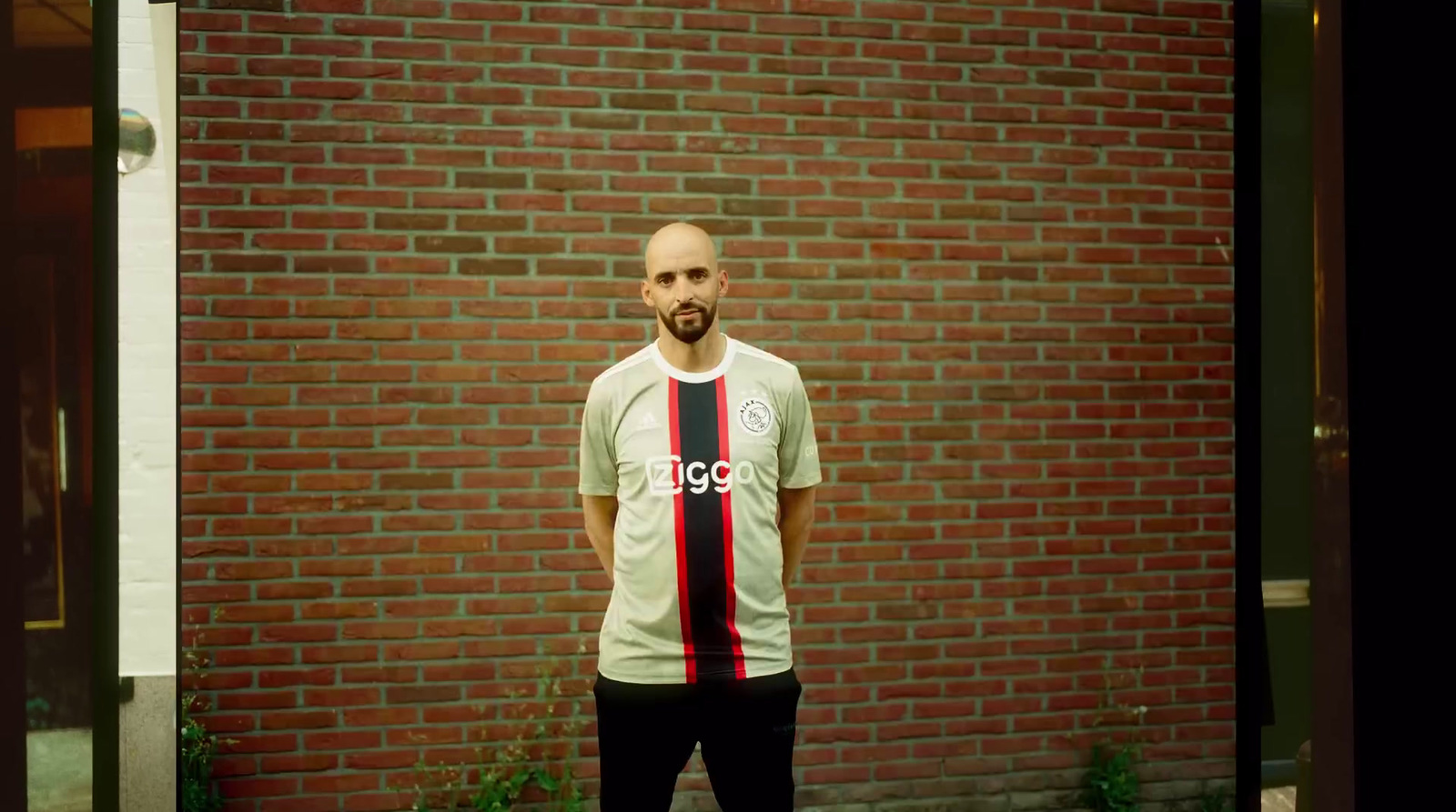 a man standing in front of a brick wall