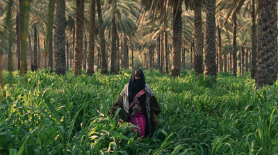 a woman walking through a lush green forest