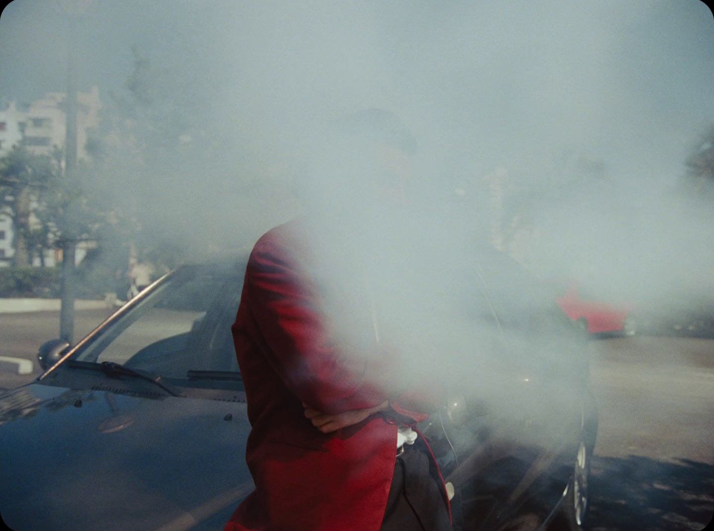 a man in a red suit standing next to a car