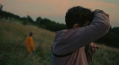 a man standing in a field holding his head