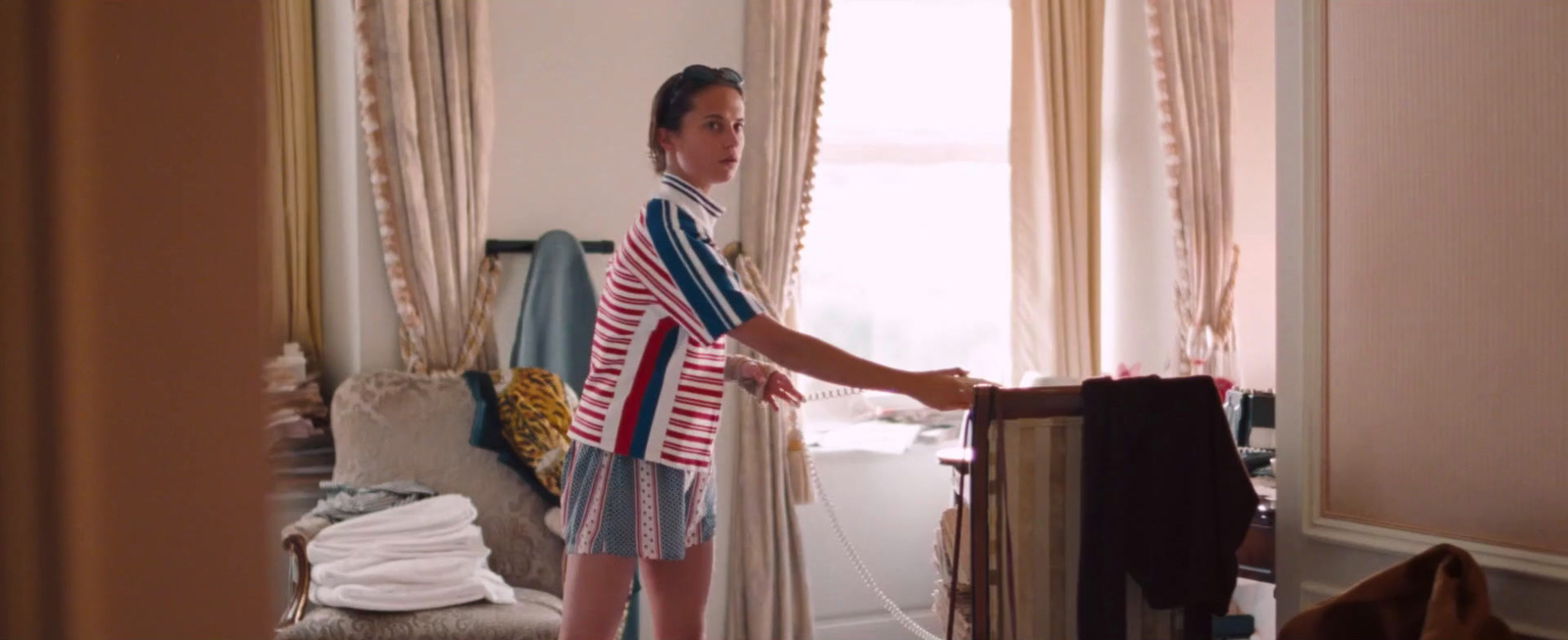 a woman standing in a room holding a shirt