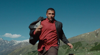 a man in a red shirt is running in the mountains