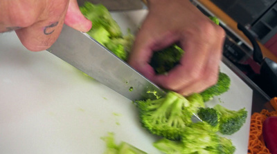 a person cutting broccoli on a cutting board