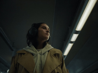 a woman in a trench coat listening to headphones