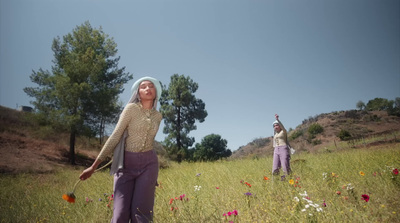 a couple of people standing in a field of flowers